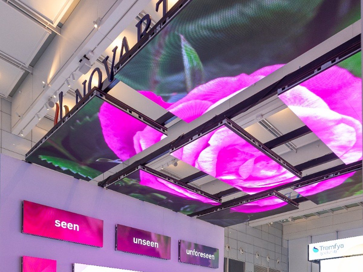 Stepped LED ceiling panels carrying a magenta rose, the Novartis name raking across above.