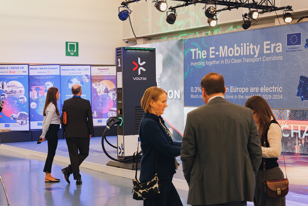 The floor in use: visitors moving between the partner totems, the charger and the headline wall.