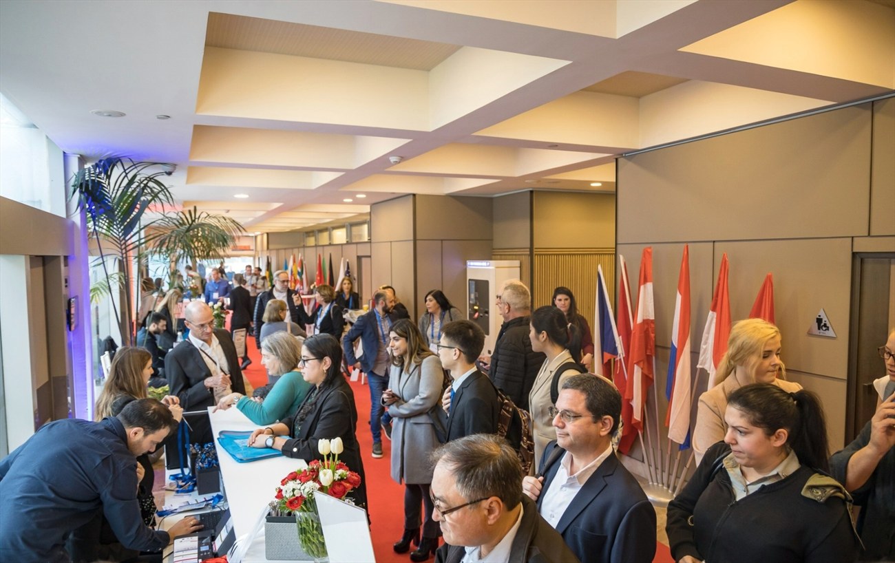 A registration desk with national flags ranged along the wall behind it.