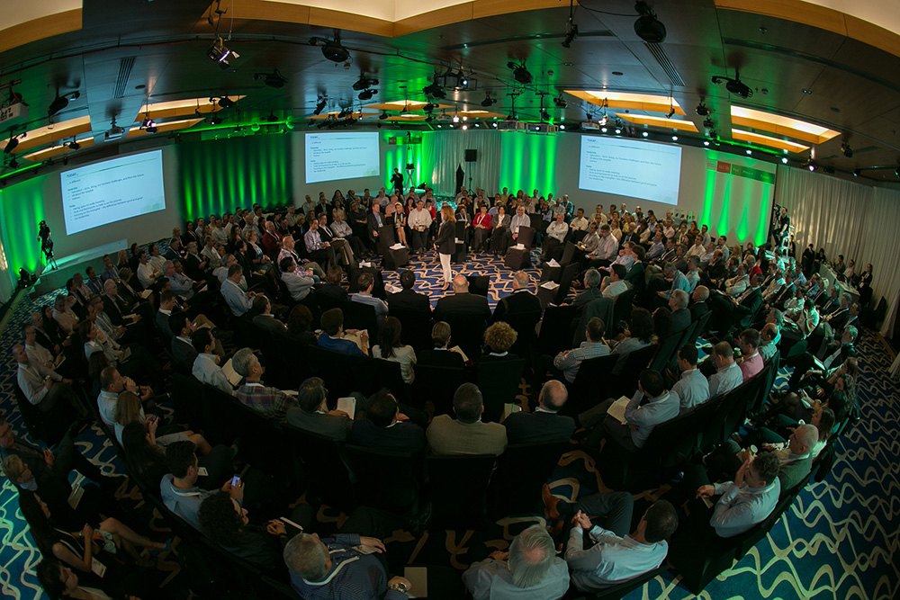 The plenary from above, the audience seated in a full circle around an open floor.