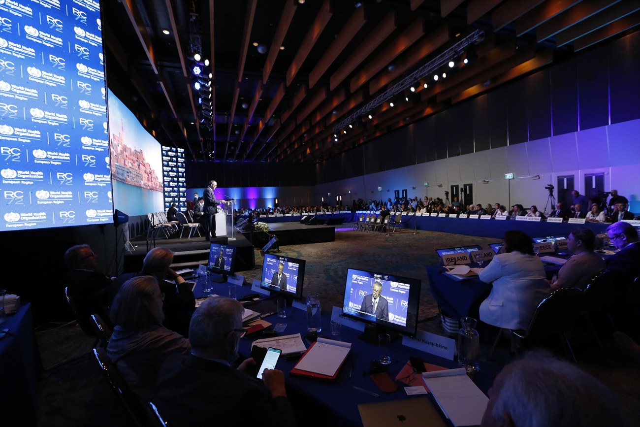 The hall in session, seen from the back, delegate desks lit by their monitors.